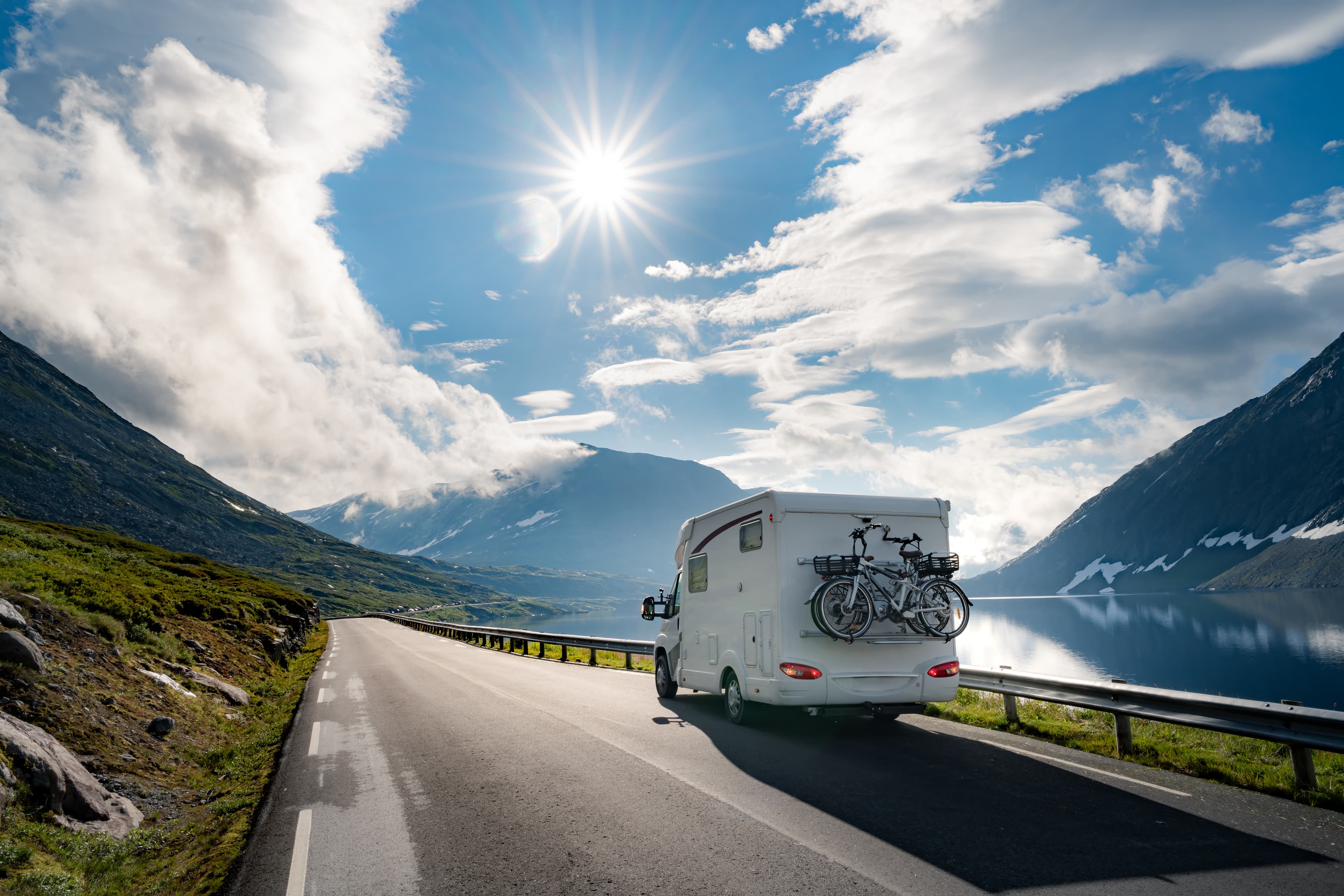 A motorhome traveling a scenic mountain highway on a bright day